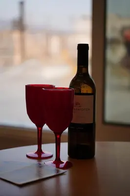 a bottle of wine and two red glasses on a table at 360 Athens Rooftop Nest, 300m from Metro Station, Acropolis View in Athens