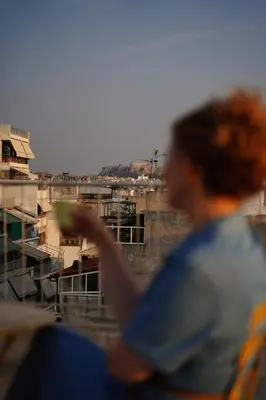 a man looking out of a window at a city at 360 Athens Rooftop Nest, 300m from Metro Station, Acropolis View in Athens