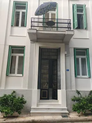a building with a door and a balcony with an umbrella at Golden room 3 in Athens