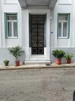 a front door of a white house with potted plants at Golden room 6 in Athens