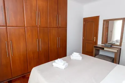 a bedroom with wooden cabinets and a bed with white sheets at Olive Grove Villa in Koropíon