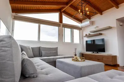 a living room with a couch and a tv at Olive Grove Villa in Koropíon