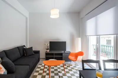 a living room with a black couch and orange chairs at 2BR Family Apartment With Playroom-Arcade, 2 Bathrooms & 2 Kitchens in Athens