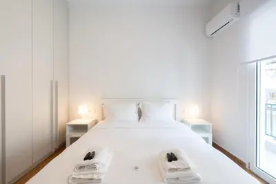 a bedroom with a white bed with two white shoes on it at 2BR Family Apartment With Playroom-Arcade, 2 Bathrooms & 2 Kitchens in Athens