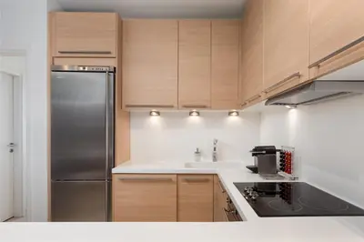 a kitchen with wooden cabinets and a stainless steel refrigerator at Vouliagmeni Exclusive Residence in Athens