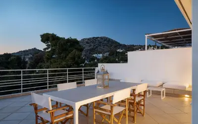 a dining table and chairs on a balcony at Vouliagmeni Exclusive Residence in Athens