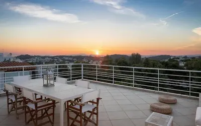 a white table and chairs on a balcony with the sunset at Vouliagmeni Exclusive Residence in Athens