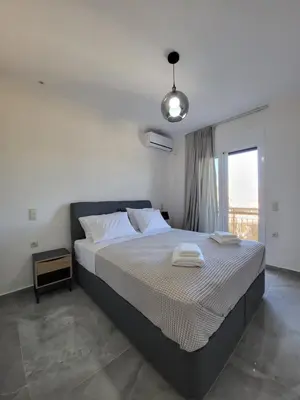 a bedroom with a large bed and a window at Luxury apartment center of Varkiza Resort in Vari