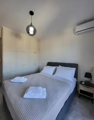 a bedroom with a bed with two towels on it at Luxury apartment center of Varkiza Resort in Vari