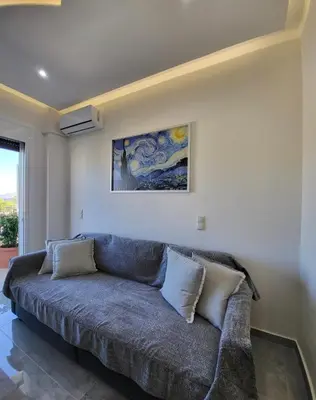 a couch in a living room with a painting on the wall at Luxury apartment center of Varkiza Resort in Vari