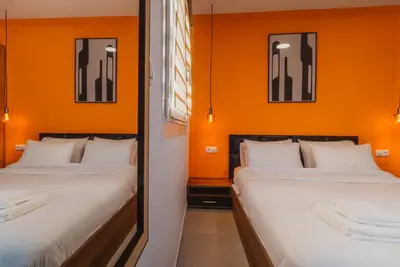 two beds in a room with orange walls at Calmio Athens 2 in Athens