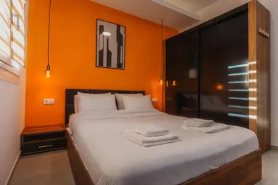 a bedroom with orange walls and a bed with towels on it at Calmio Athens 2 in Athens