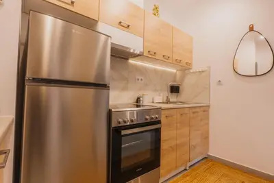 a stainless steel refrigerator in a kitchen with wooden cabinets at Calmio Athens 2 in Athens
