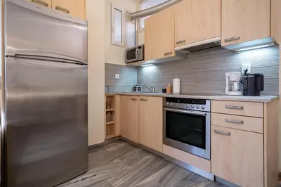 a kitchen with a stainless steel refrigerator and wooden cabinets at Plaka City Studio - Walk to Syntagma by ΜΡS in Athens