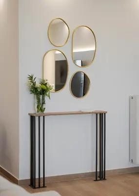 a console table with three mirrors on a white wall at Majestique South Riviera Residence in Athens