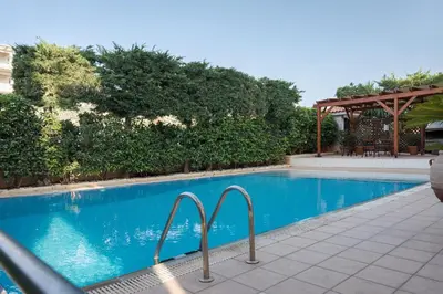 a blue swimming pool with a gazebo at Majestique South Riviera Residence in Athens