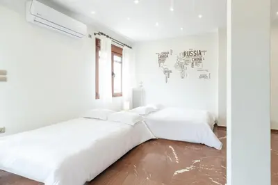 two beds in a bedroom with white walls and wood floors at Luxury, entire, 2-10 person apartment in ilioupoli in Athens