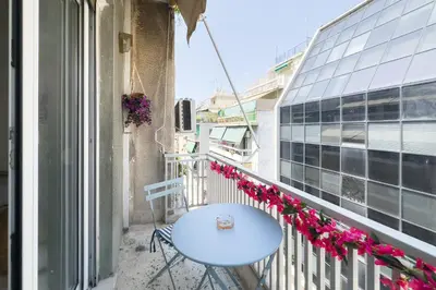 a balcony with a blue table and flowers at Comfort Athens Apartment near Metro Station in Athens