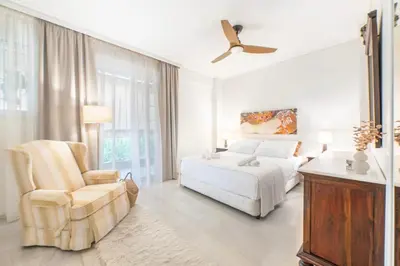 a white bedroom with a bed and a chair at Pure Azure in Athens