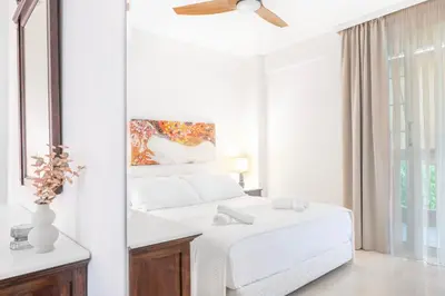 a white bedroom with a bed and a ceiling fan at Pure Azure in Athens