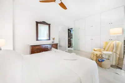 a white bedroom with a bed and a chair at Pure Azure in Athens