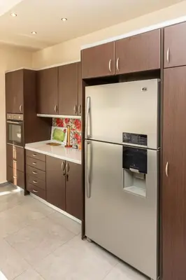 a kitchen with a stainless steel refrigerator and wooden cabinets at Vasso Villa in Vravrona
