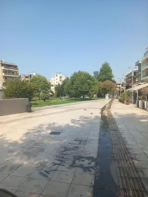 an empty street in a city with trees and buildings at Αpt in Gazi in front of metro in Athens