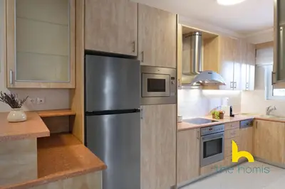 a kitchen with a stainless steel refrigerator and wooden cabinets at Athens Riviera APT, Near Seaside with Private Parking in Athens