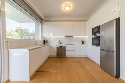 a kitchen with white cabinets and a large window at Anlijors Premium Residency in Kalívia Thorikoú