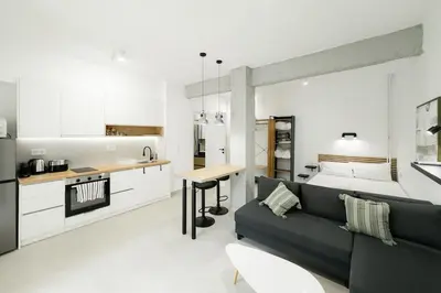a living room with a black couch and a kitchen at Studio Garden next to Metro station in Piraeus