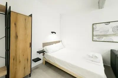 a small bedroom with a bed and a wooden door at Studio Garden next to Metro station in Piraeus