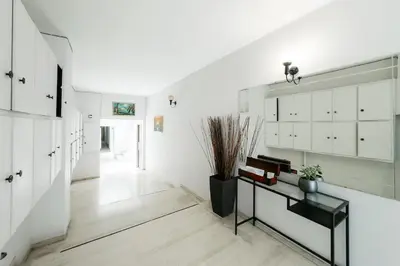 a hallway with white cabinets and a table with plants at Studio Garden next to Metro station in Piraeus