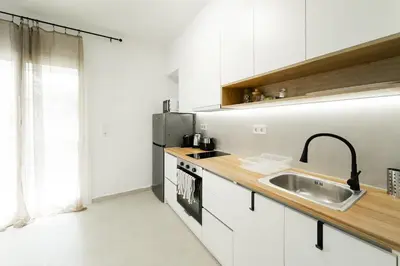 a white kitchen with a sink and a microwave at Studio Garden next to Metro station in Piraeus