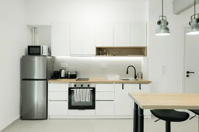 a kitchen with white cabinets and a stainless steel refrigerator at Studio Garden next to Metro station in Piraeus