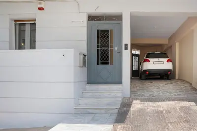 a white house with a blue door and a car at Athens Apartment on Lycabettus Hill with Rooftop View Access in Athens