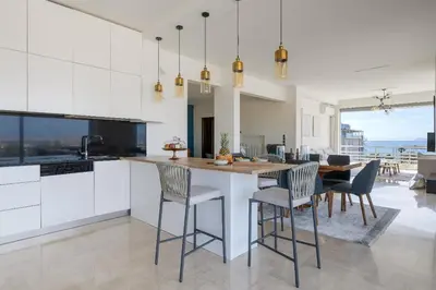 a kitchen with white cabinets and a table with chairs at 3 Bedroom Apartment in Glyfada in Athens