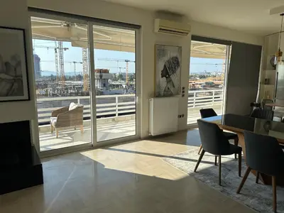 a living room with a table and chairs and a balcony at 3 Bedroom Apartment in Glyfada in Athens