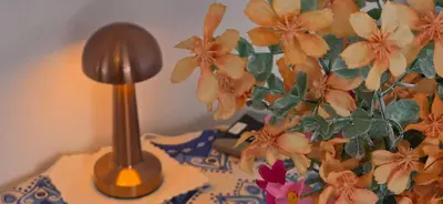 a lamp on a table next to a vase with flowers at Helen's holiday home in Athens
