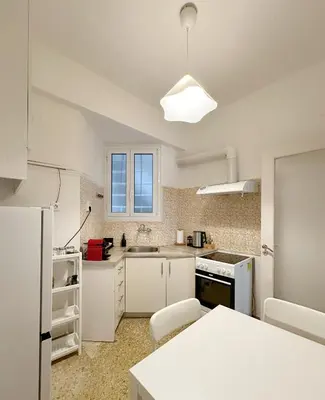 a kitchen with white cabinets and a white refrigerator at Acropolis Nest in Athens