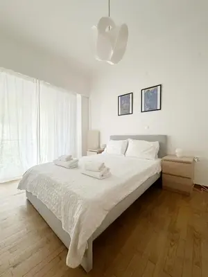 a white bedroom with a large bed with white sheets at Acropolis Nest in Athens