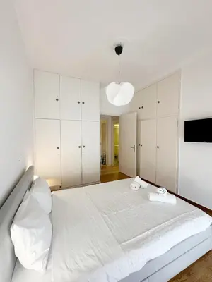 a white bedroom with a large bed with white cabinets at Acropolis Nest in Athens