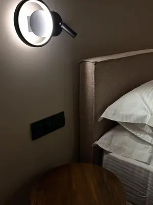 a bedroom with a table and a lamp next to a bed at Χenion Inn - Athens Airport, Easy Check In Anytime in Markopoulo