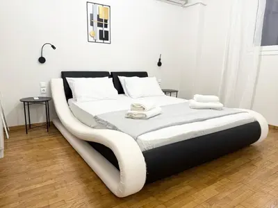 a large white bed with a black frame in a room at Gyzi Comfort Apartment in Athens