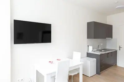 a white kitchen with a table and a tv on the wall at Urban Athens - Studio #3 in Athens