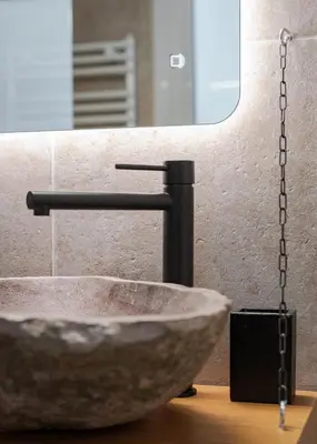 a bathroom with a stone sink and a mirror at Nostos Athens Luxury Residence in Athens