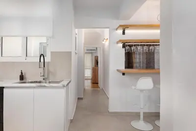a kitchen with white cabinets and a sink and a chair at Nostos Athens Luxury Residence in Athens