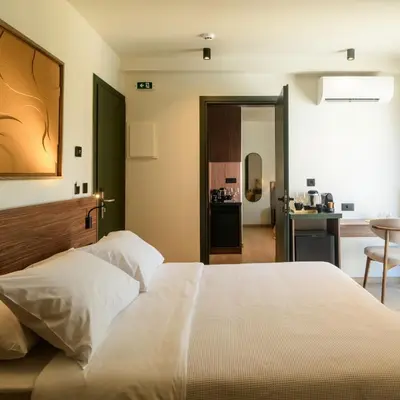 a bedroom with a large white bed and a kitchen at Ermou 26 Hotel in Athens