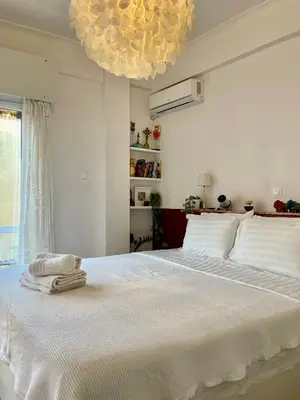 a bedroom with a large white bed with a chandelier at Colorful Apartment Close to the Acropolis in Athens