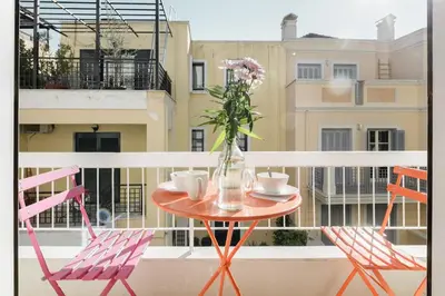 a table with two chairs and a vase with flowers on a balcony at Colorful Apartment Close to the Acropolis in Athens