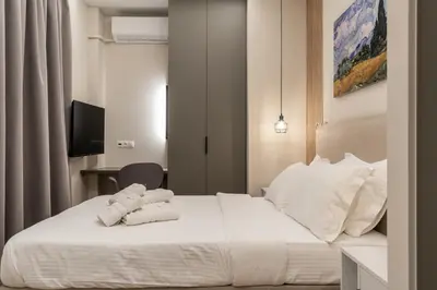 a bedroom with a bed with white sheets and pillows at The Minion Elegant Suite Piraeus in Piraeus